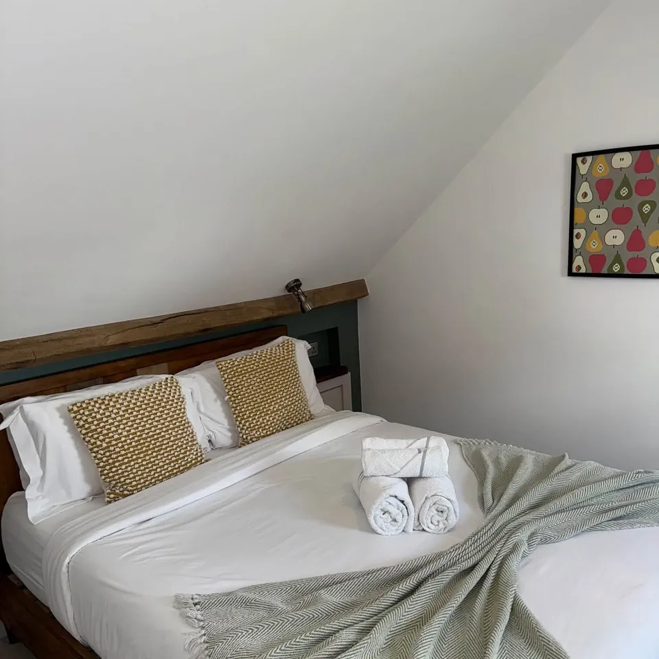 A loft bedroom with a freshly made bed and rolled towels