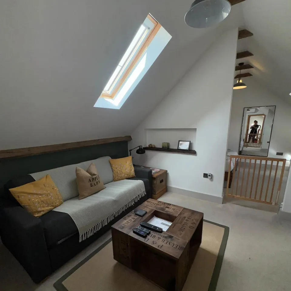 A loft living room left tidy, with a hoovered carpet and plumped cushions