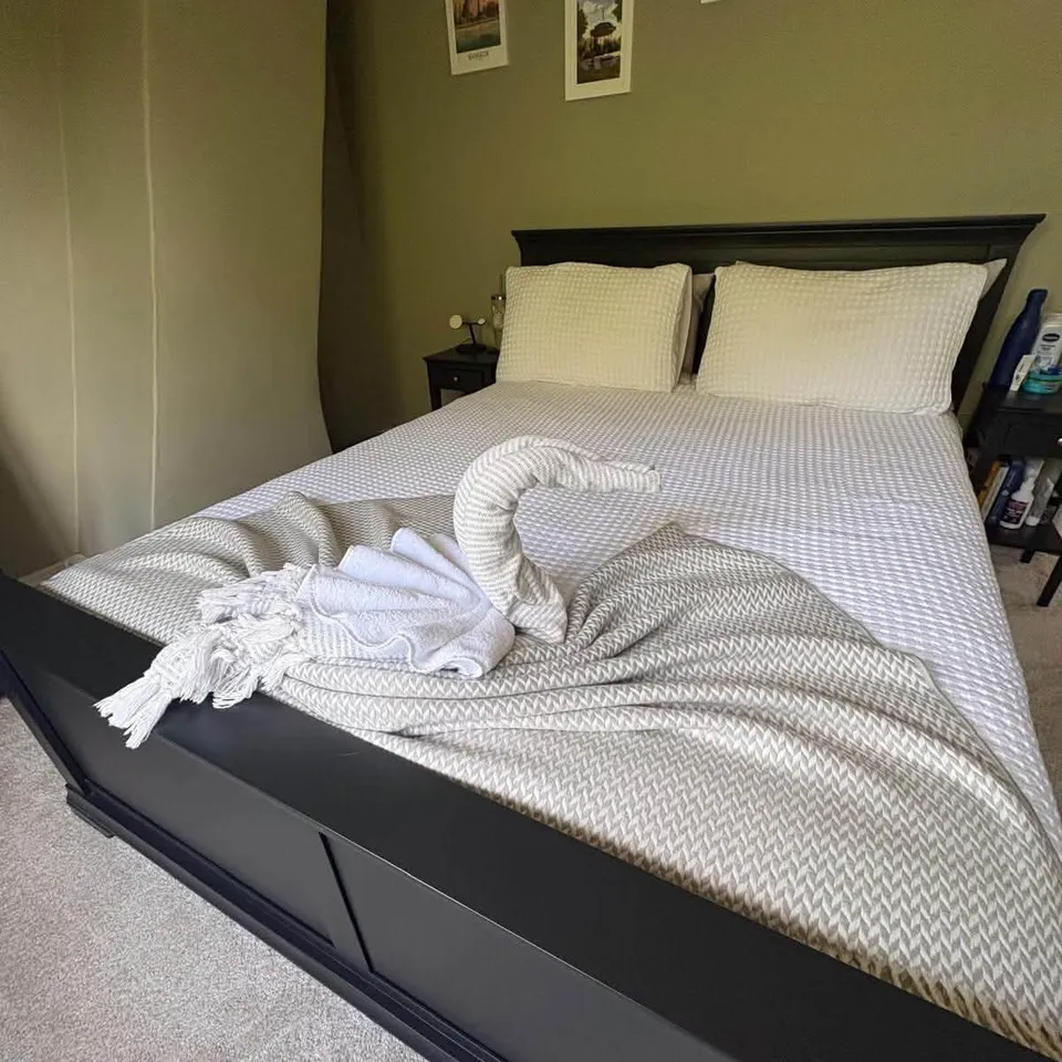 A towel folded into a swan on a freshly made double bed