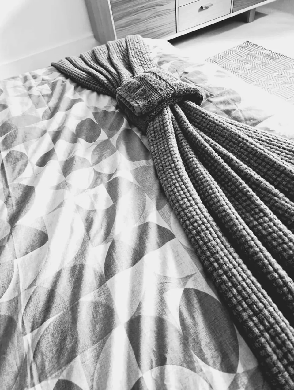 A dressing gown folded and tied in a neat bow on a freshly made bed